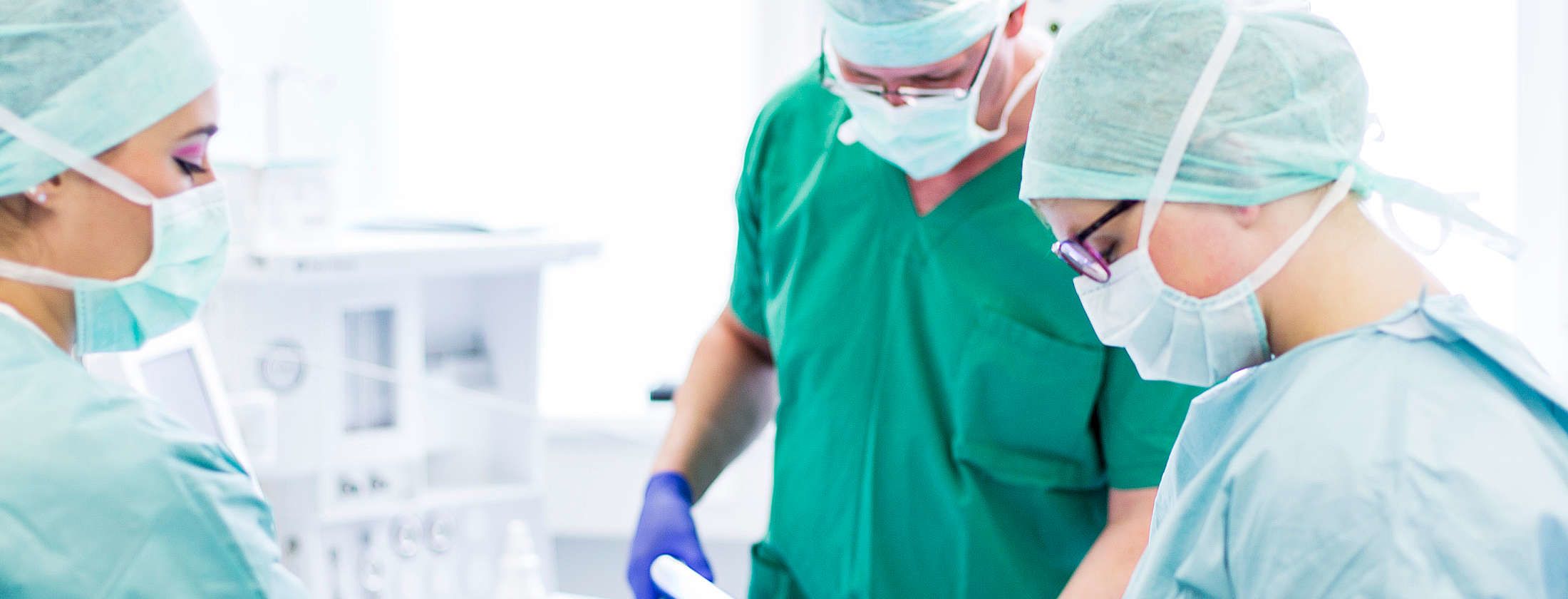 Хирурги и медсестры при пластической операции в частной клинике Франкфурта, ФРГ. Специализированный персонал одет в специальную одежду ради гигиены. Врачи выполняют с помощью хирургических инструментов пластическую и эстетическую операцию.