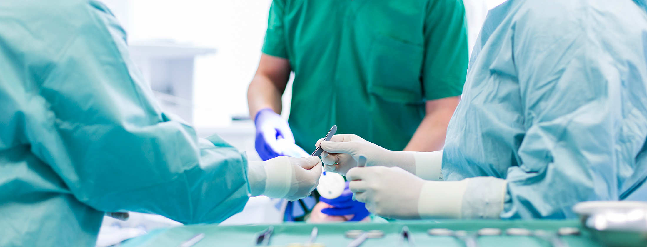 Chirurgen bei einer Operation in der Berger Klinik Frankfurt bei einem allgemeinen operativen chirurgischen Eingriff. Fachärzte und OP-Schwestern hantieren mit chirurgischen Instrumenten. Im Vordergrund steht eine OP-Ablage mit weiteren Utensilien.